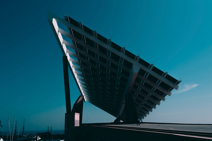 Large angled solar panel installation with modern architectural design, set against a clear blue sky.