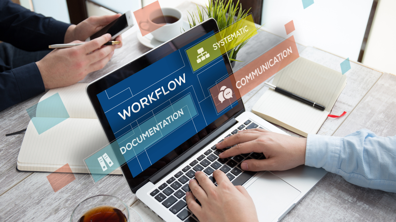 Hands typing on a laptop displaying the word 'Workflow' with related terms: Documentation, Communication, and Systematic.