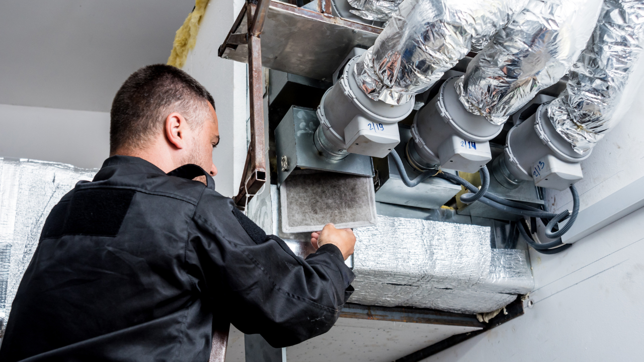 Technician performing maintenance on an HVAC ventilation system